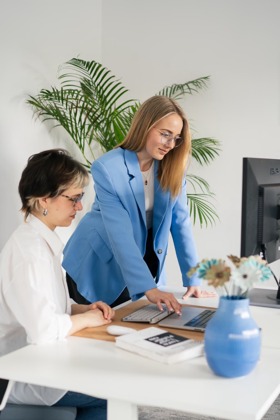 Dwie projektantki Beevision pracują razem przy laptopie w biurze
