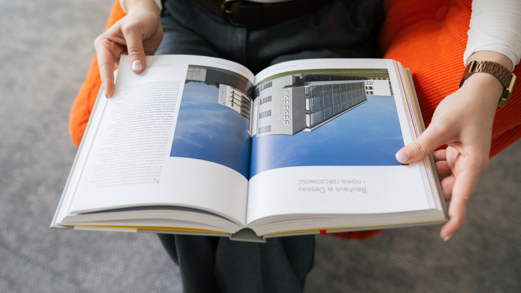 Otwarty katalog z fotografiami architektury w dłoniach