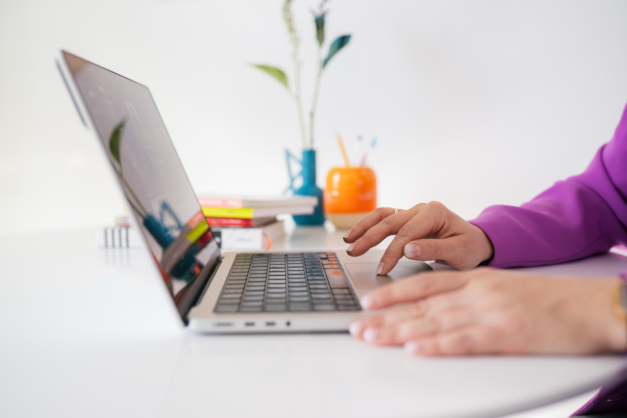 Dłonie piszące na laptopie przy jasnym biurku – projektowanie strony internetowej